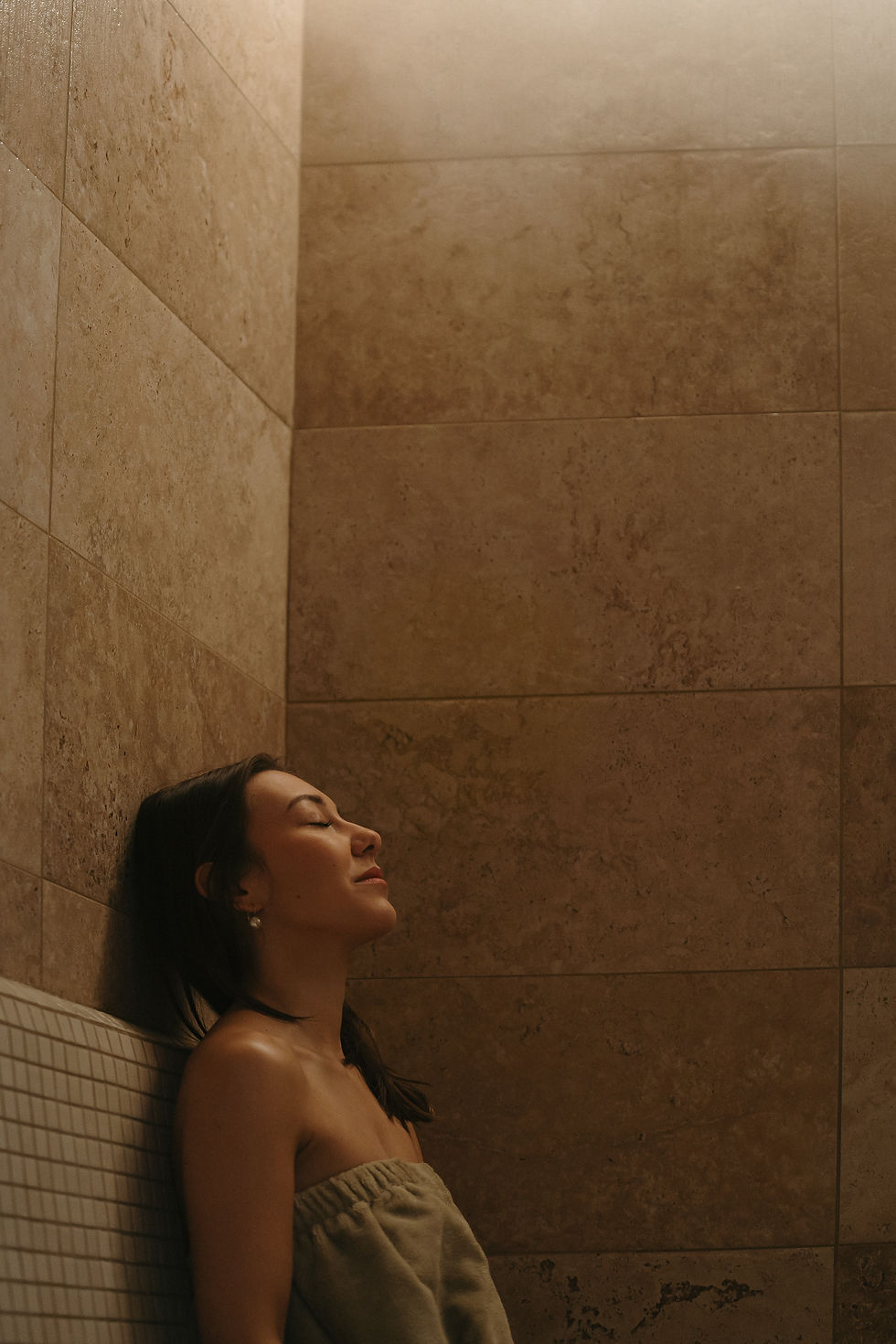 Femme aux yeux clos se relaxant dans un sauna ou spa.