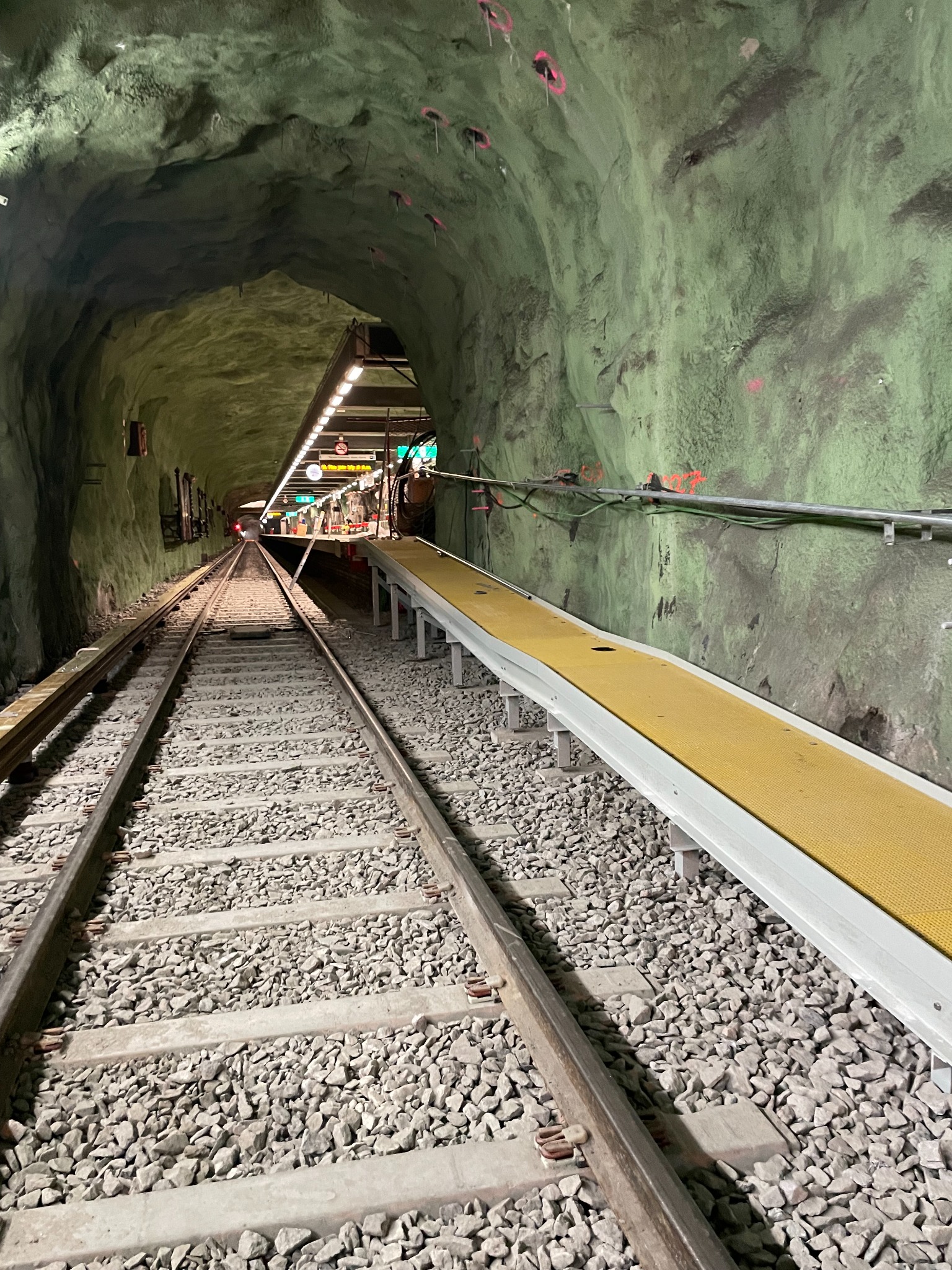 Utrymningsramp med gul gångyta längs spåret i Stockholms tunnelbana