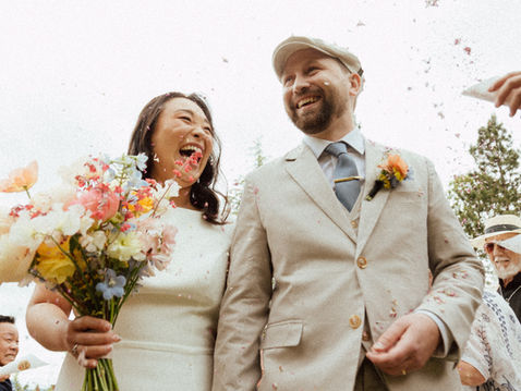 Seulbi and Cody share a joyful moment during their summer wedding ceremony at Villa Eyrie Resort with the lush Malahat mountains in the background.
