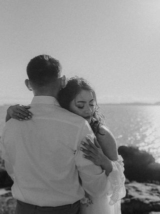 Couple embracing near the historic Fisgard Lighthouse with ocean views in the background