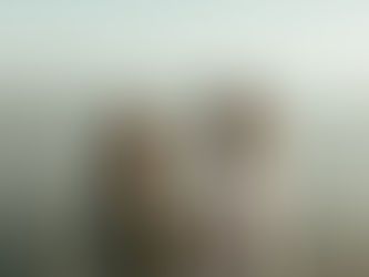 Cecilia & Chris holding hands during their surprise proposal at Whiffin Spit in Sooke BC, looking out at sparkling water and mountains, captured by a Victoria BC engagement photographer.