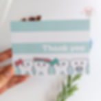 Hand holding a green and white striped thank you card with cute tooth characters