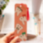 Hand holding a pink bookmark featuring whimsical tooth characters
