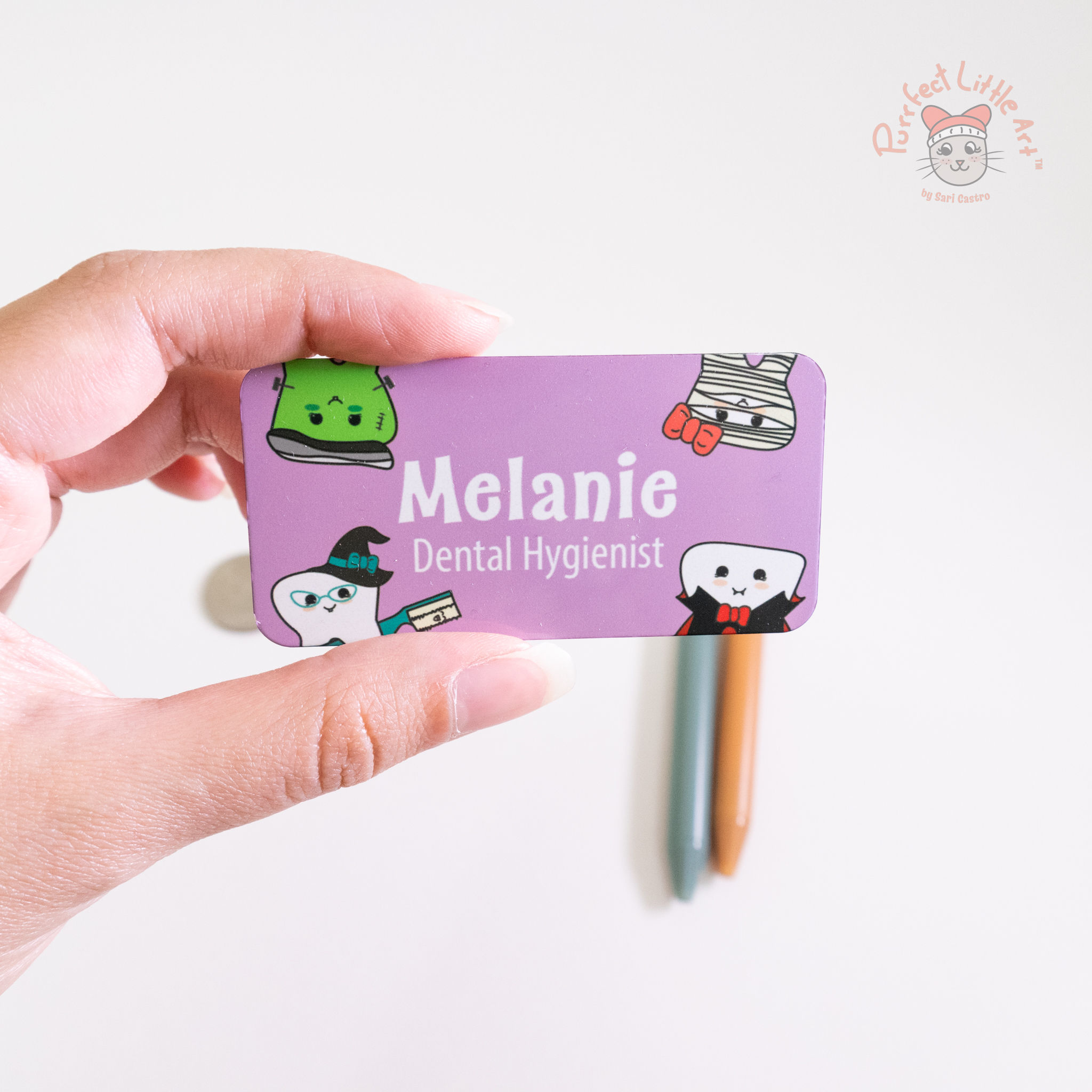 Hand holding a dental halloween themed name tag.