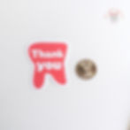 Pink tooth-shaped sticker next to a coin