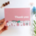 Hand holding a pink thank you card with whimsical tooth characters