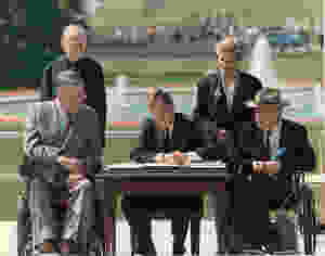 President George H. W. Bush signing the ADA at desk outdoors with four individuals on either side, two of whom are seated in wheelchairs.