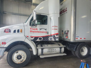 A diesel-powered Truck Maintenance vehicle parked inside a service bay, ready for duty in Fort Wayne, IN, featuring a logo celebrating 40 years of service.