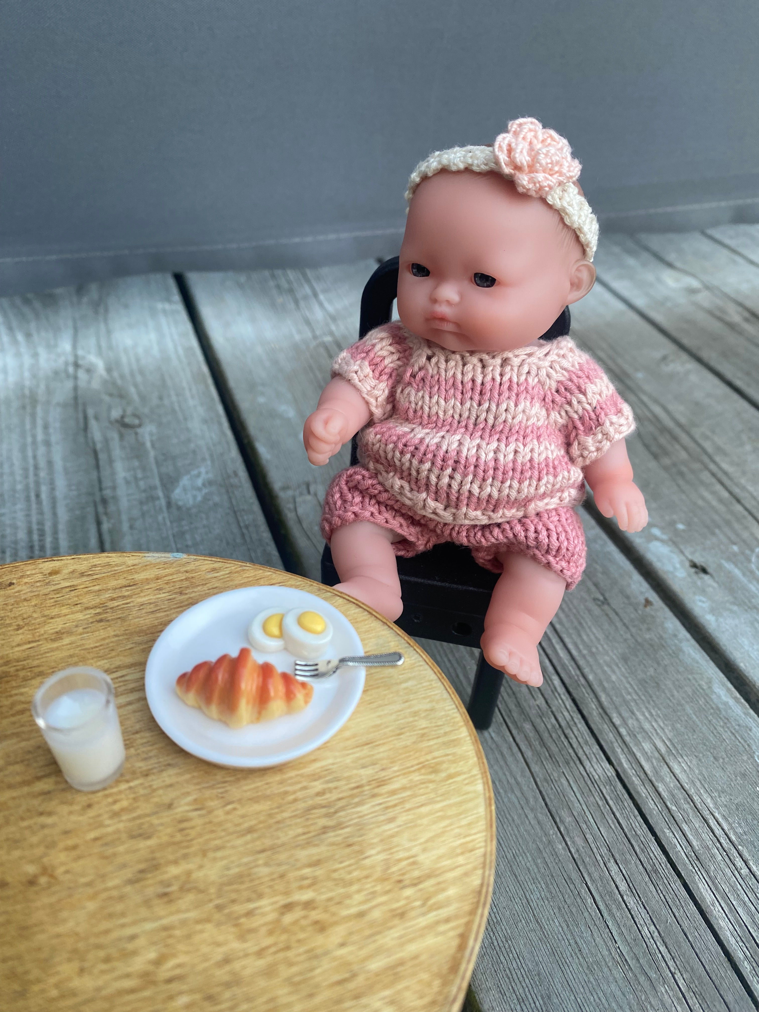 Spisesett med tallerken, gaffel, melkeglass, egg og croissant