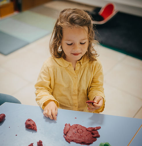Une enfant qui manipule de la pâte à modeler
