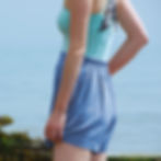 Side profile of model wearing denim blue linen blend shorts paired with a mint green bodysuit