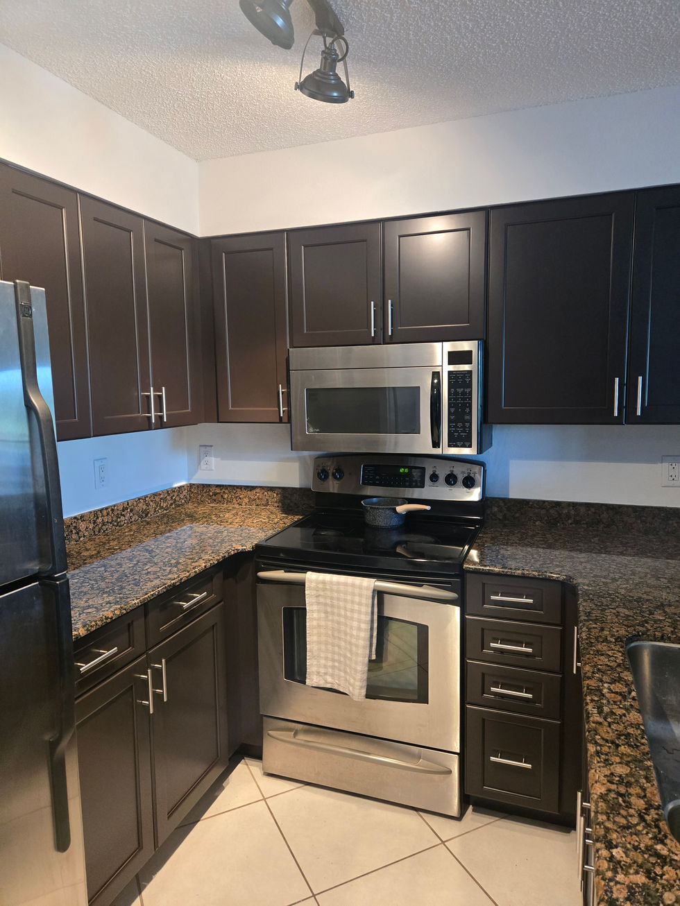 Dark espresso brown kitchen cabinets with granite countertops and stainless appliances, custom finishing