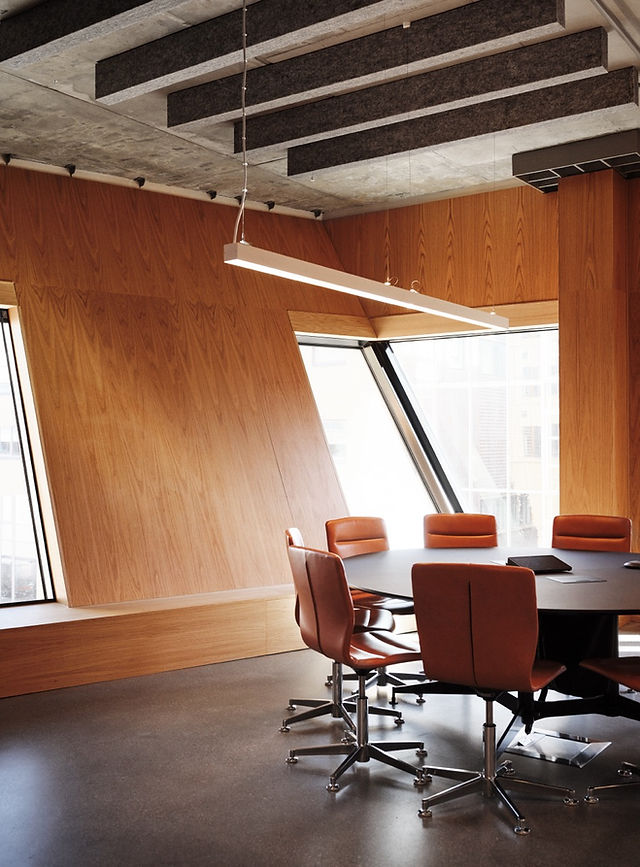 Interior of an office space in Vertikal Nydalen, featuring exposed concrete ceilings, natural light from large windows, and sustainably sourced furnishings. The design emphasizes comfort and sustainability, with clay-coated walls and embedded water pipes for natural temperature regulation.