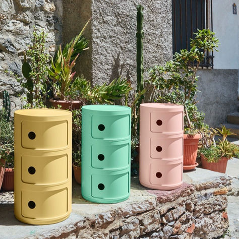 Stacked Componibili Bio modular storage units by Kartell, made from sustainable bioplastic in soft natural tones (yellow, green, pink). Iconic cylindrical design reimagined with eco-friendly materials, reflecting Italian design heritage and environmental responsibility.