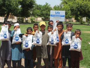children holding up bags of udhiyah meat. 