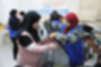 Photo of Life for Relief and Development (LIFE) team member helping a young lady put on a winter coat.