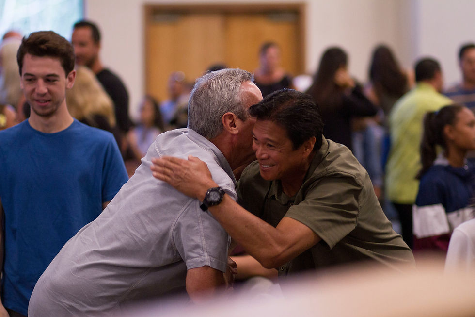A warm embrace captures the genuine connection between two friends amid a lively gathering.