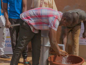 Photo of a man enjoying the fresh, clean water pouring out of the Life for Relief and Development USA (LIFE) water well. 