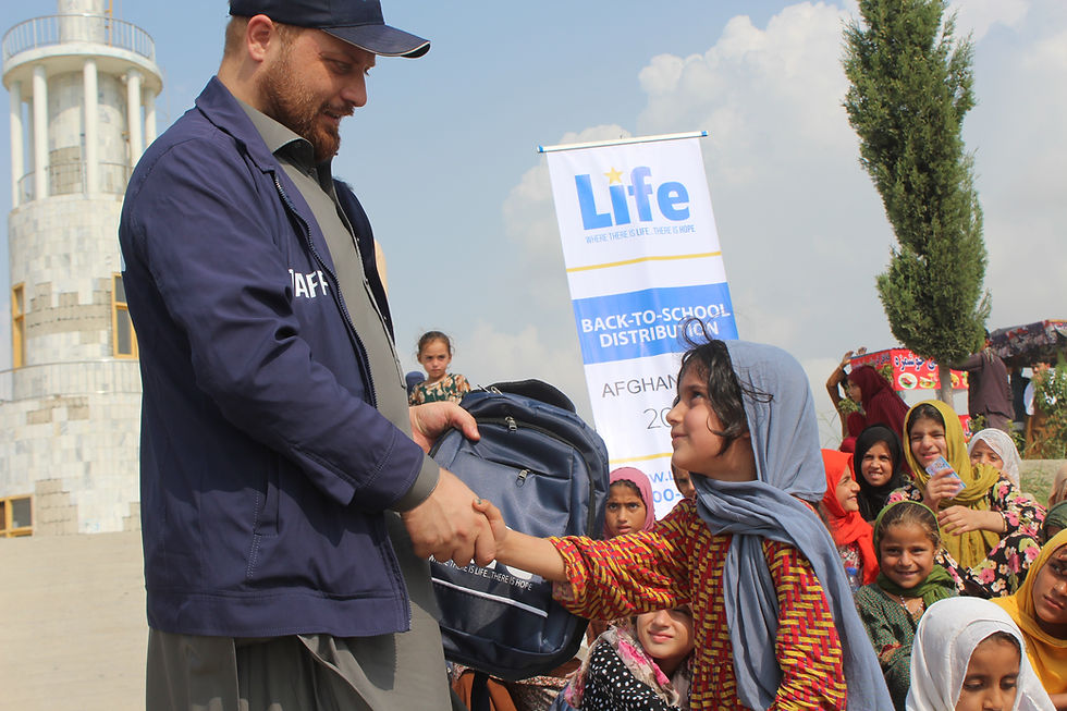 Photo of a young girl receiving a Life for Relief and Development USA (LIFE) backpack from a LIFE team member in Afghanistan.