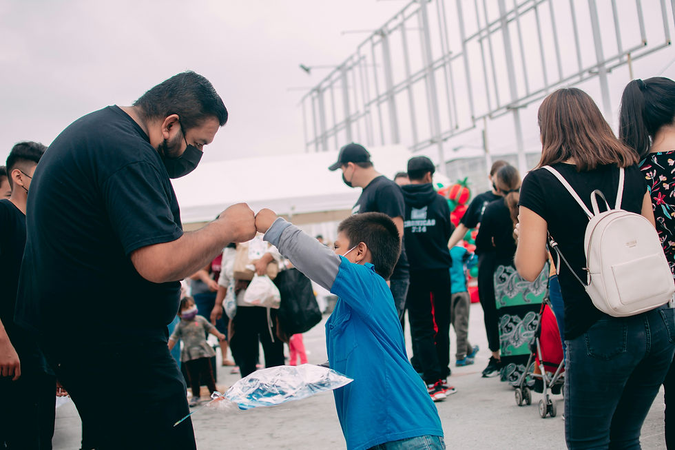 A man and a child share a friendly fist bump during a bustling outdoor event, surrounded by a crowd of people.