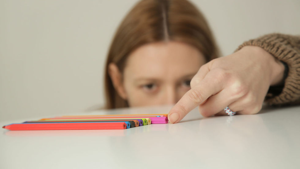 Eine Frau richtet akribisch farbige Stifte auf einem Tisch aus – ein typisches Verhalten bei Ordnungs- und Kontrollzwängen. Das Bild veranschaulicht den inneren Drang zur Perfektion und die Herausforderung, solche Zwänge zu besiegen.