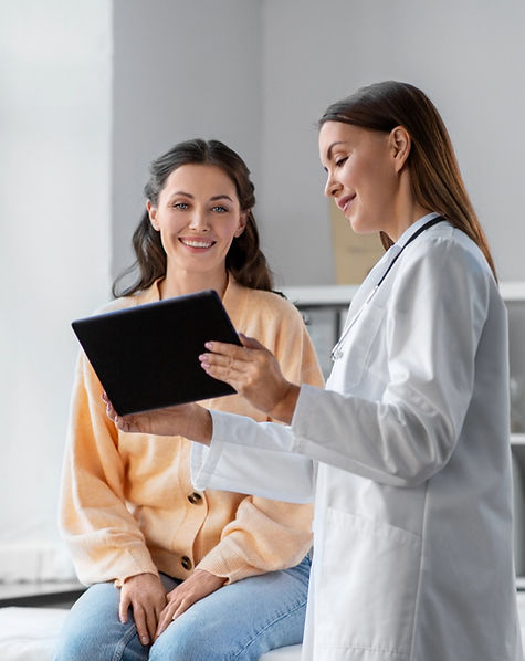 Ärztin bespricht Diagnose am Tablet mit lächelnder Patientin.