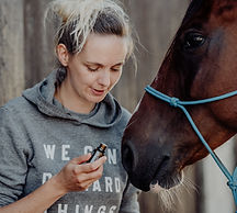 Frau riecht an Öleflasche mit Pferd