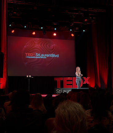 Andrea Ross delivering her TEDx talk on stage at TEDxStLaurentBlvd