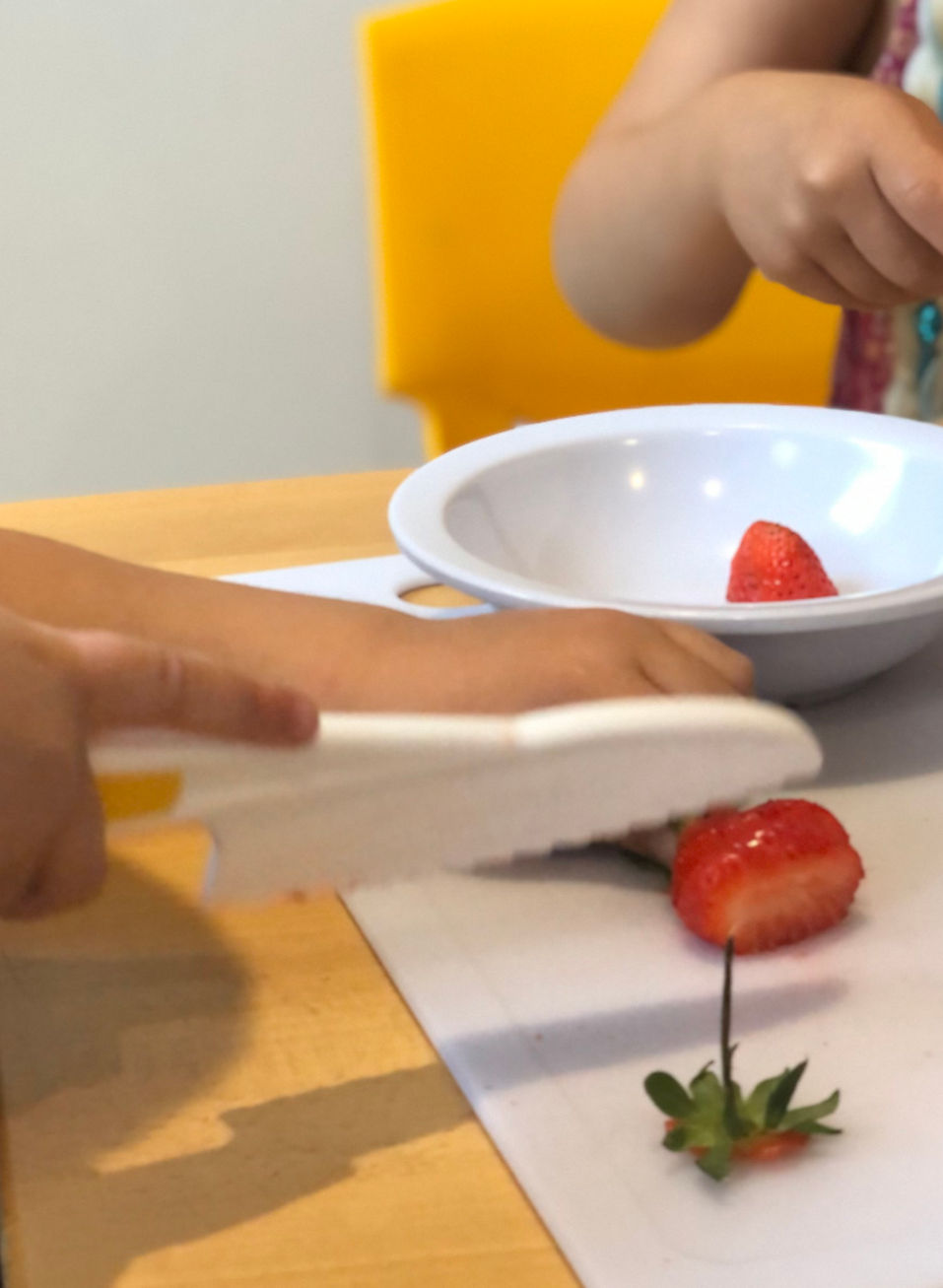 Two children chopping up strawberries