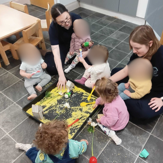babies playing with a tray of yellow oobleck