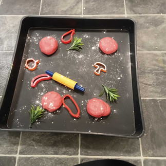 a tray with red playdough and petals/ leaves