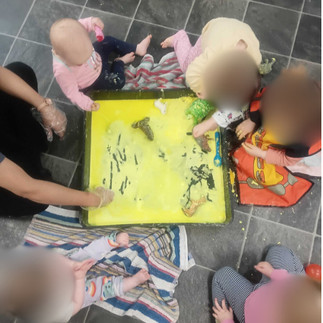babys playing with a tray filled with yellow oobleck