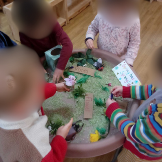 toddlers playing with a tray full of green coloured rice