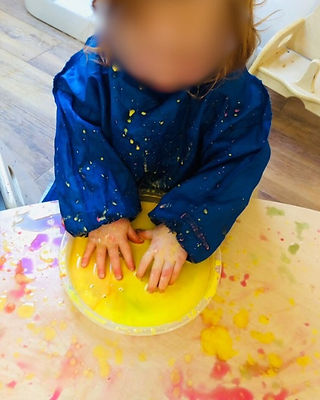 child splashing their hands in coloured paing
