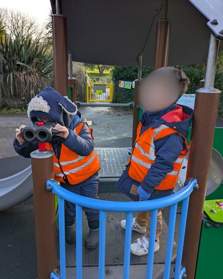 two children looking out binoculars at a play park