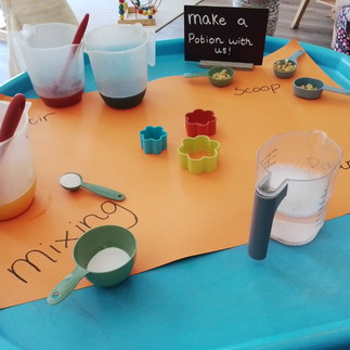 a tray with various jugs, bowls and spoons full of coloured water for mixing and stiring