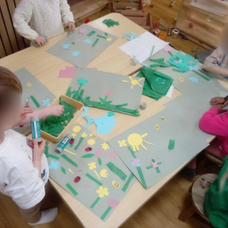 preschoolers at a table cutting out sun shapes , flower shapes and stalks
