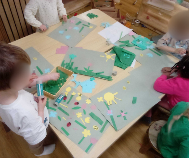 preschoolers at a table cutting out sun shapes , flower shapes and stalks 