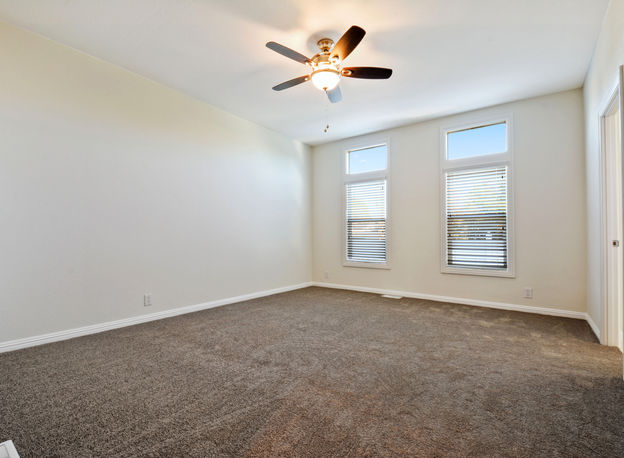 Spacious bedroom with ceiling fan and carpet