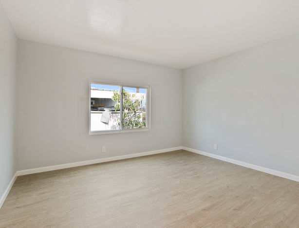 Bright bedroom with window, wood-look floors