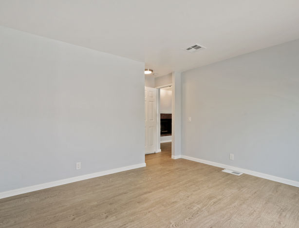 Spacious room with light grey walls and wood-look flooring