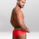 Miniatura: Hombre con ropa interior roja y banda dorada con la marca Speedo, posa