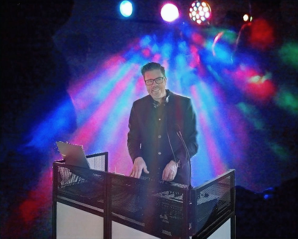 DJ Wibert bakom DJ-båset med färgstark festbelysning