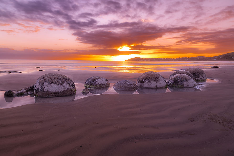 Stunning Moeraki Boulders at sunrise and low tide with the light reflecting off the water.