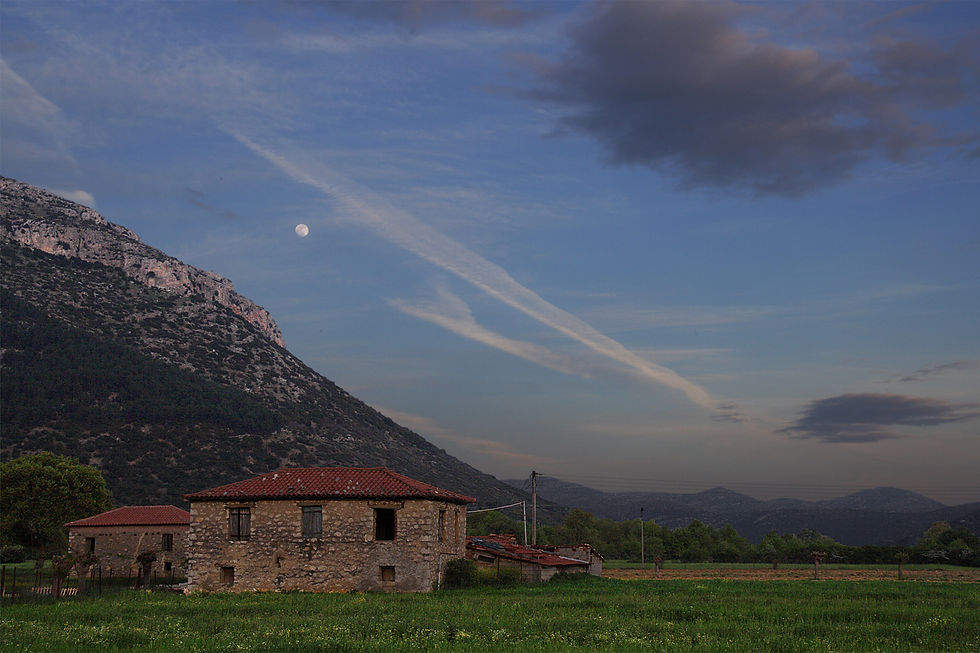 Traditional stone house against a mountain backdrop on the Mantinia plain at moonrise