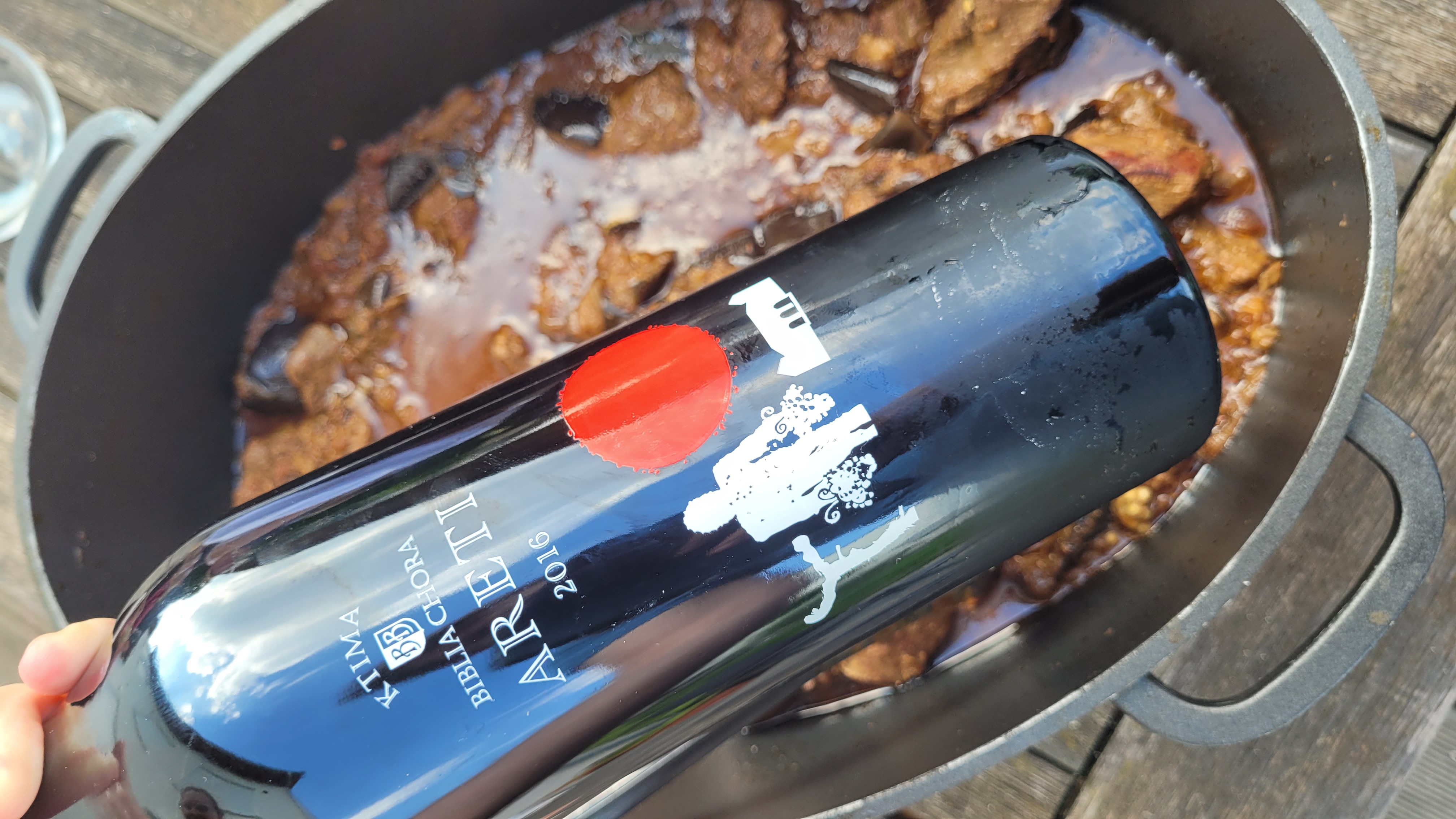Bottle of Ktima Biblia Chora Areti 2016 above a pot of wild boar and aubergine stew