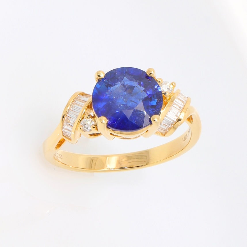 A gold gemstone engagement ring with channel-set baguette diamonds and round diamond accents.