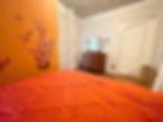 Month to month fully furnished rental bedroom with orange bed.