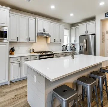 Finished kitchen remodel in McKinney TX featuring painted cabinets quartz countertops large island and wood-look tile flooring