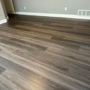 Luxury vinyl plank flooring installed in a Prosper TX bedroom with dark wood-look planks and modern gray walls